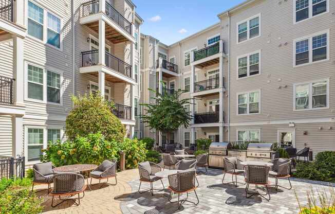 A patio with chairs and a table is surrounded by apartment buildings.