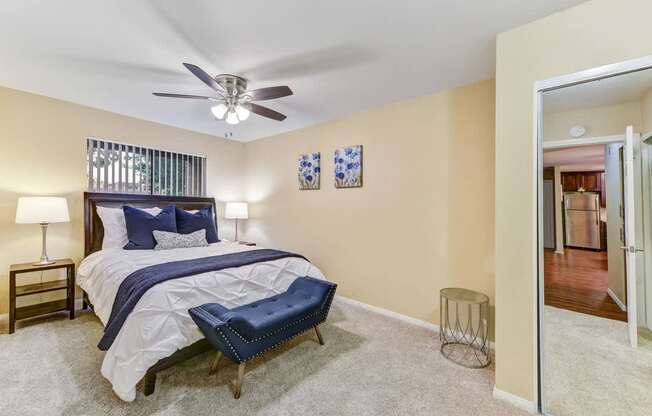 A bedroom with a bed, a chair, and a ceiling fan.