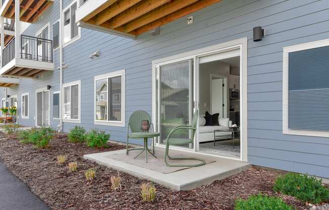 a patio with a chair and a table in front of a house