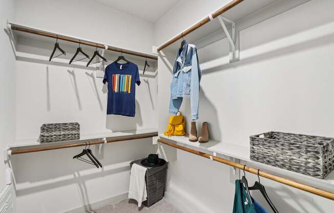 A white closet with clothes and shoes on shelves and hangers.