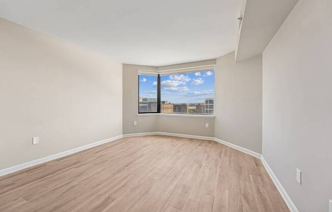Spacious bedroom with sleek plank flooring and oversized baywindow