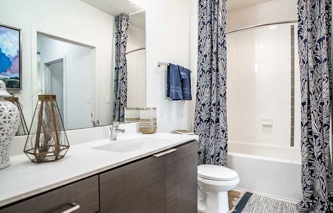 A bathroom with a white toilet, a sink, and a shower with a black and white curtain.