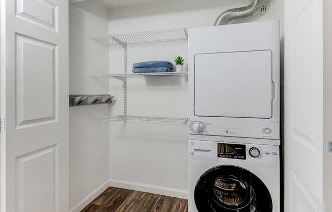 a small laundry room with a washer and dryer and a closet with shelves