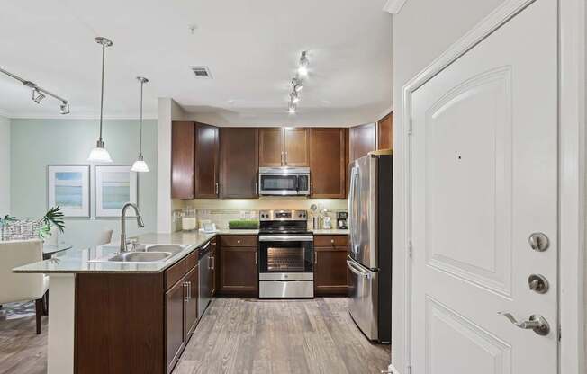 A modern kitchen with dark wood cabinets and stainless steel appliances.