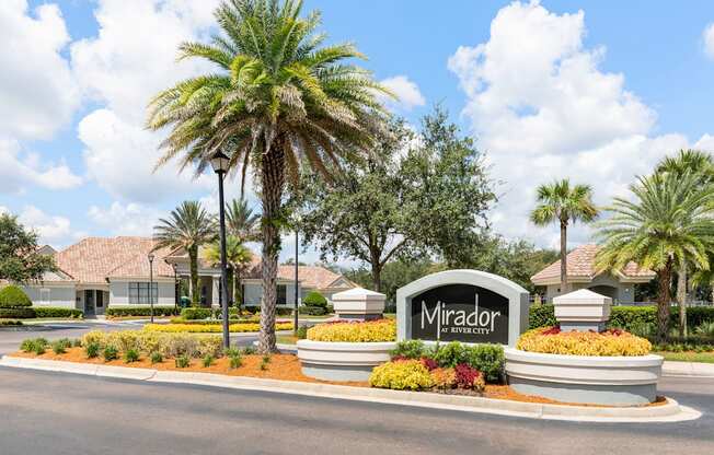 The entrance to the Mirador residential complex is surrounded by palm trees and landscaping.