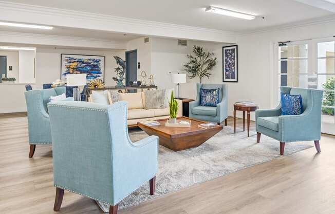 a living room with blue chairs and a couch and a coffee table