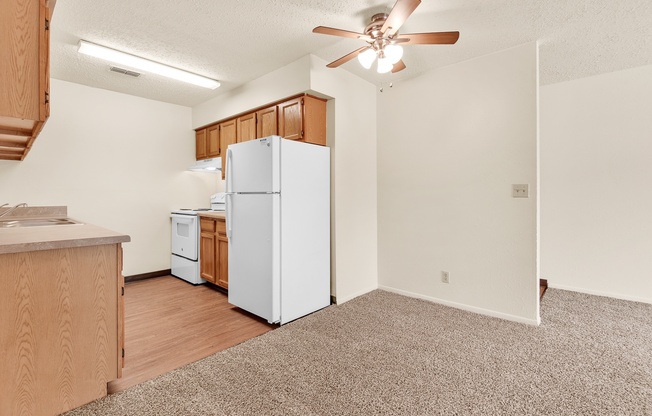 A kitchen with a white refrigerator and wooden cabinets.