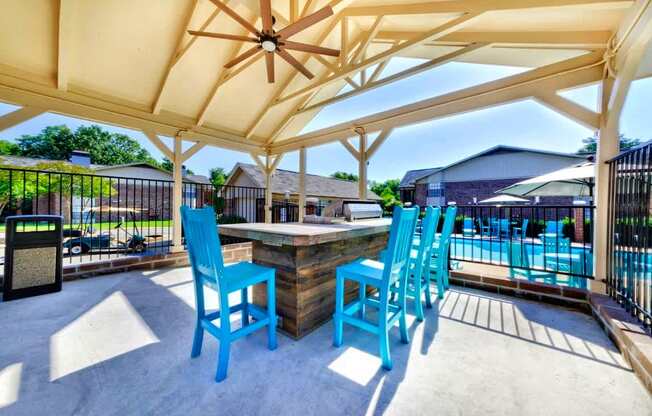 A patio with blue chairs and a table under a canopy.