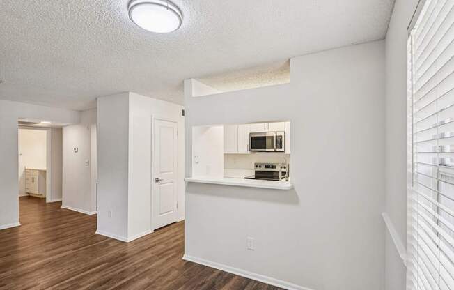 A white room with a wooden floor and a window with blinds.