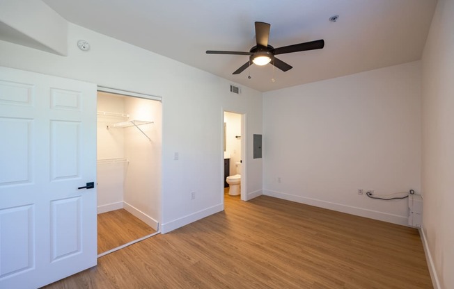 a bedroom with white walls and a ceiling fan