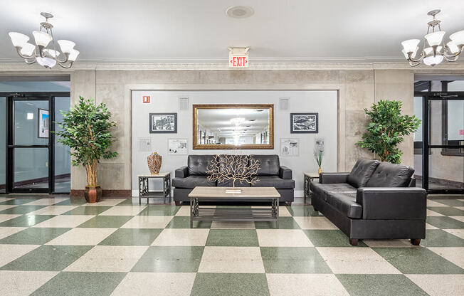 a lobby with couches and a coffee table on a checkered floor