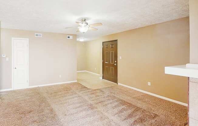 A room with a carpeted floor and a ceiling fan.