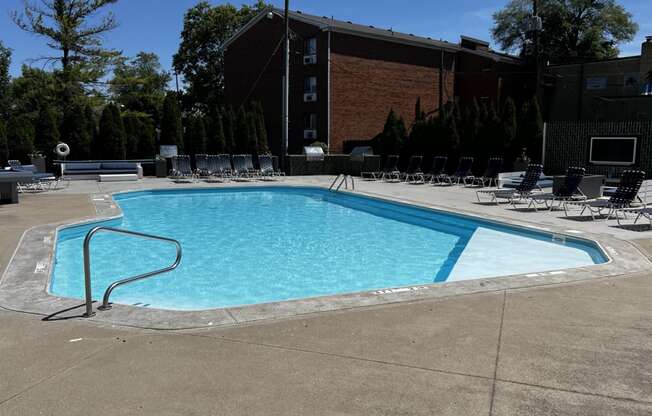 a swimming pool with chairs around it in front of a building