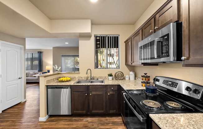 A modern kitchen with dark wood cabinets and stainless steel appliances.