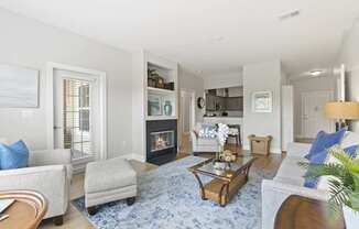 A living room with a fireplace and a blue rug.