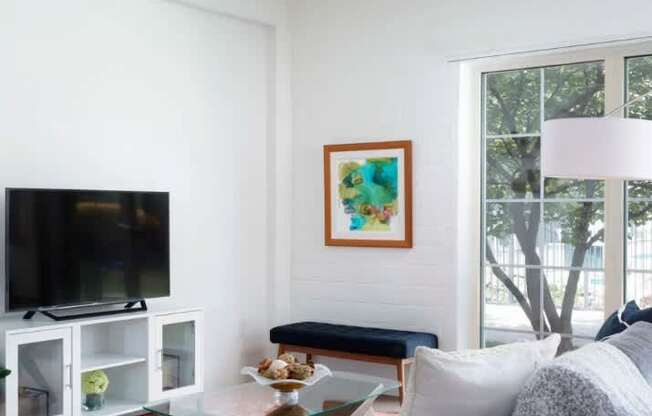 A living room with a television, a couch, and a painting on the wall.