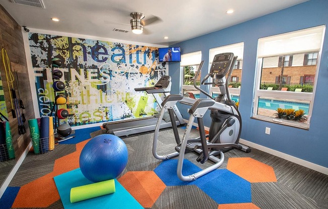 a gym with exercise equipment and a wall of graffiti