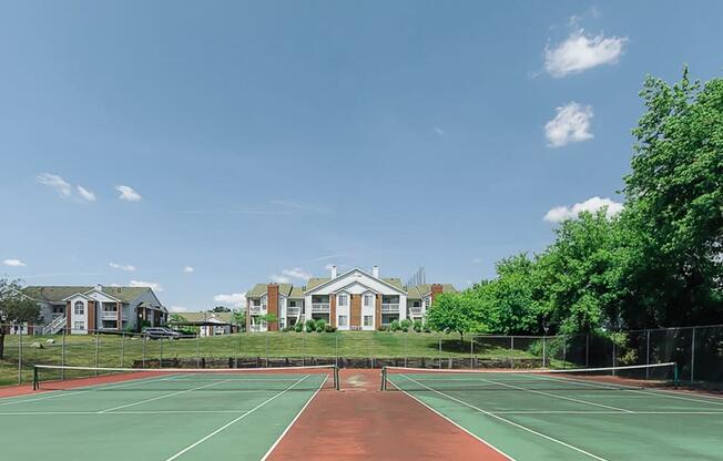 a tennis court with apartments in the background