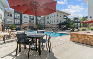 a patio with a table and chairs and a pool in the background