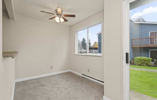 an empty living room with a ceiling fan and a window