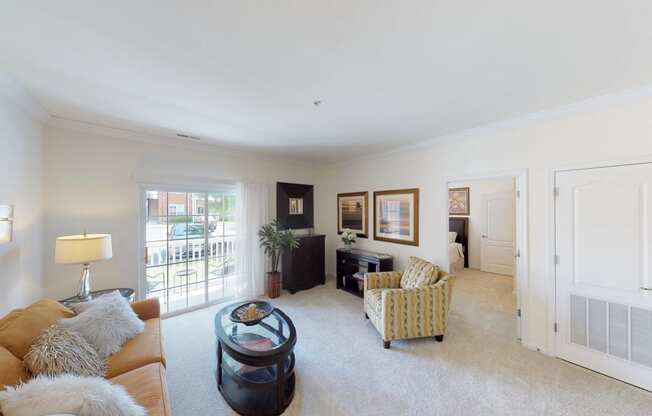 Living room with couch and chair; door to patio or balcony