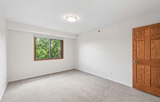 A room with a window and a carpeted floor.