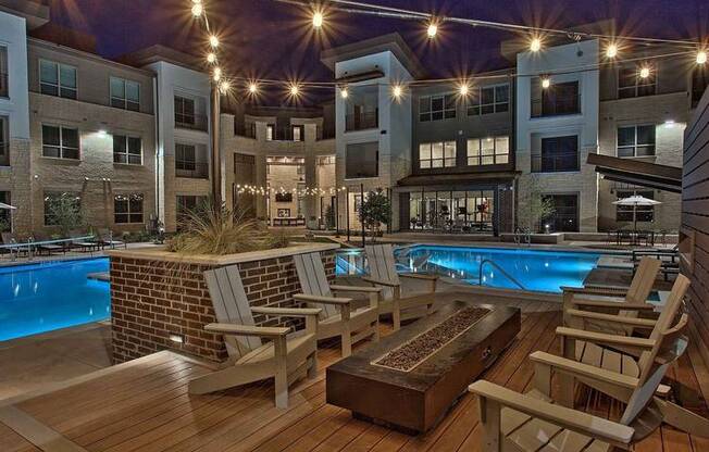 a swimming pool with rocking chairs in front of an apartment building at Hunters Creek Apartments, Denton Texas