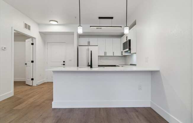 an empty kitchen with white cabinets and a white counter top