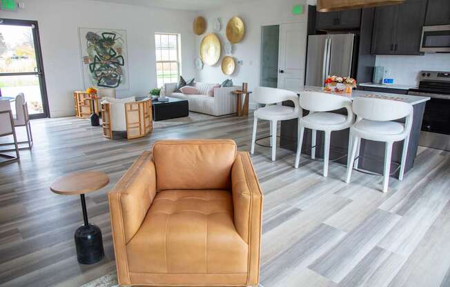 A living room with a tan leather chair and a grey floor at Evergreen Luxury Apartments, Merrillville, IN