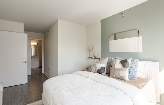 A bedroom with a large bed and a mirror above it.