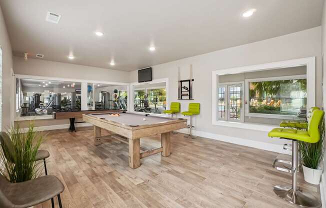 A room with a pool table and a bar area.