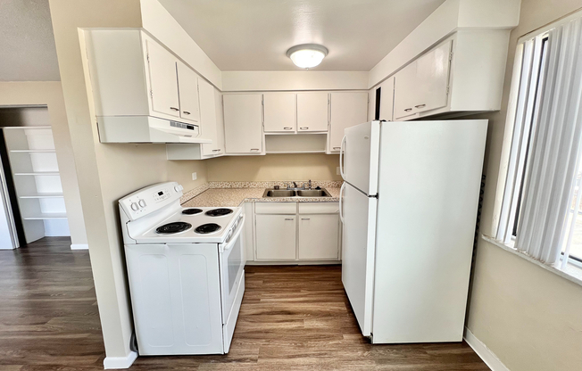Bright and inviting kitchen with white cabinetry, modern appliances, and wood-style flooring, perfect for culinary creativity.