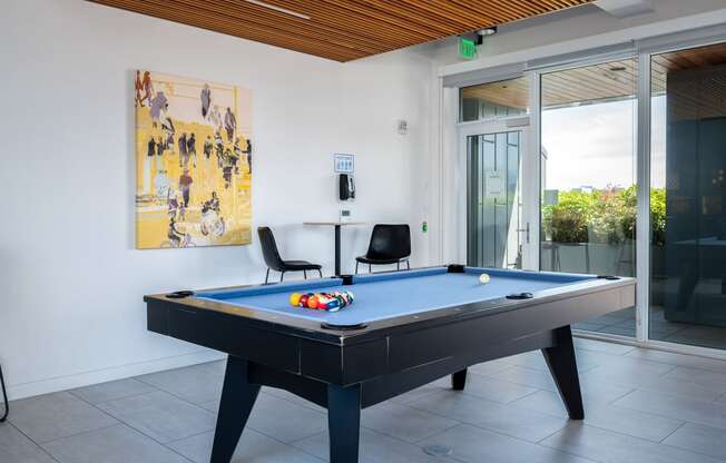 a pool table with two chairs and a painting on the wall