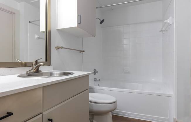 A white bathroom with a toilet, sink, and bathtub.