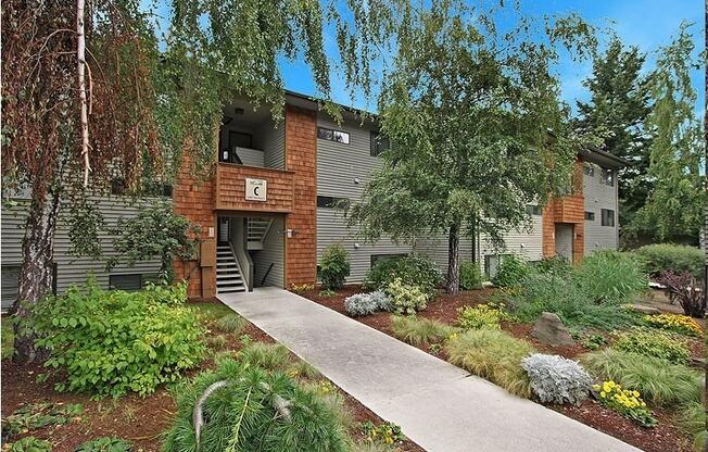a building with a sidewalk and trees in front of it