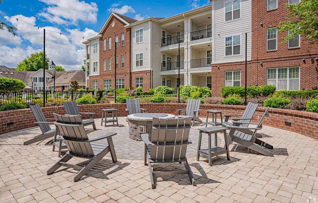 A patio with chairs and a table in front of apartment buildings.