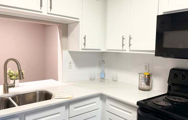 A kitchen with white cabinets and a black stove.