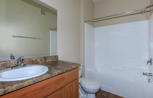 a large white tub next to a sink and a mirror