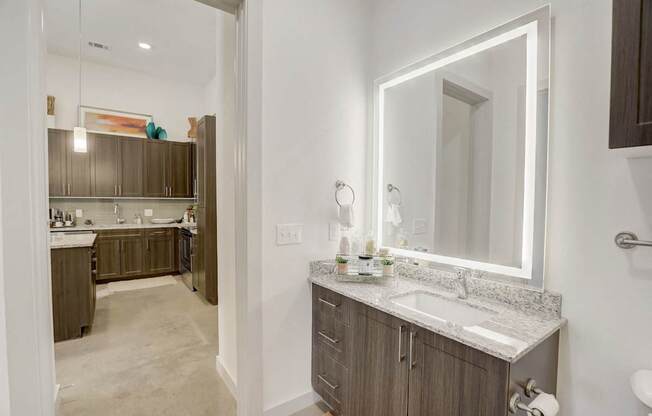 A bathroom with a sink, mirror, and cabinets at Infinity on the Point Apartments, Dallas 75243