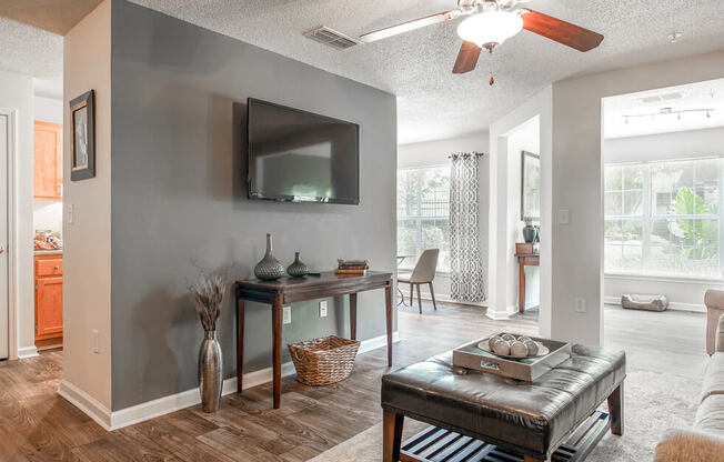 A living room with a grey wall and a flat screen TV mounted on it.