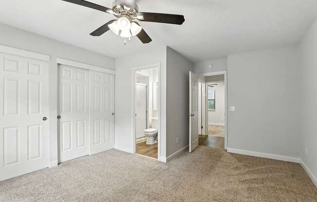A room with a ceiling fan and carpeted floor.