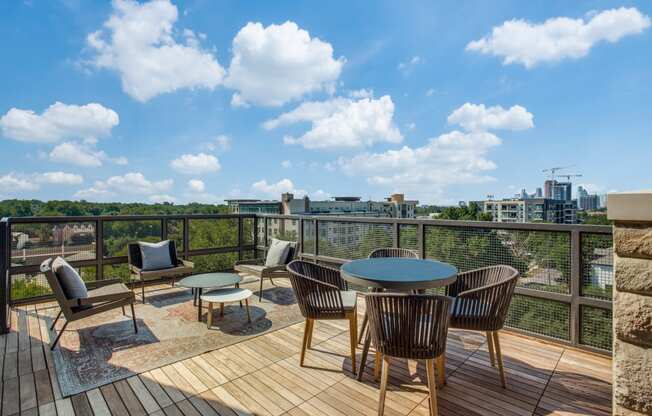 a patio with a round table and chairs on a wooden deck with a view of the city