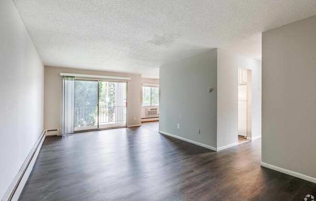 an empty living room with hard wood floors and a balcony