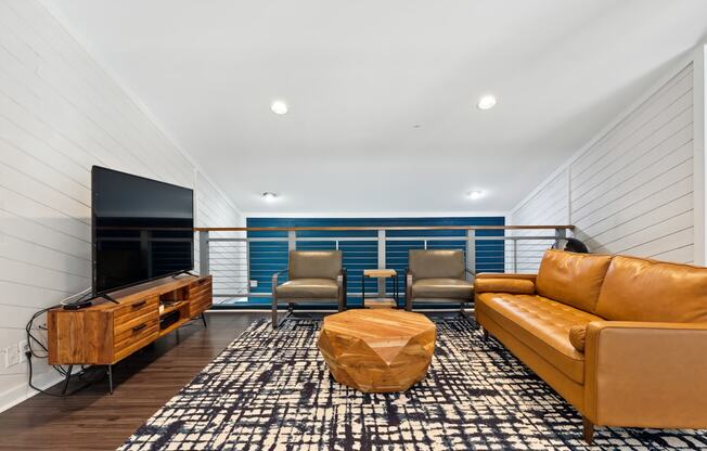 a living room with a leather couch and chairs and a flat screen tv on the wall at Linkhorn Bay Apartments, Virginia Beach