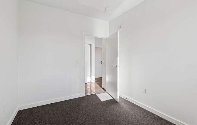 A hallway with a carpeted floor and white walls.