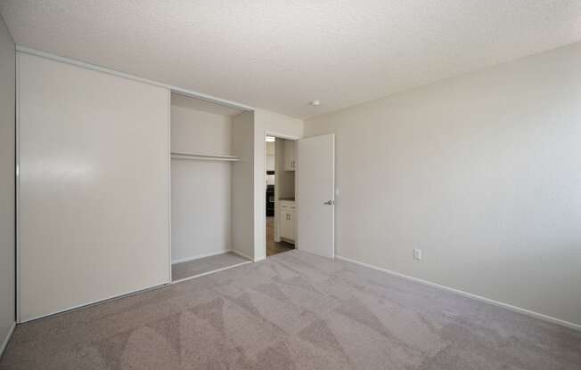 an empty bedroom with a door to a closet