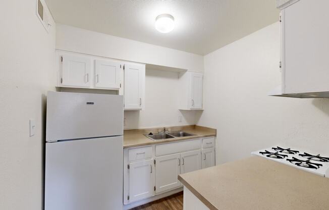 a kitchen with white cabinets and a refrigerator and a sink at La Terraza, Phoenix, 85018