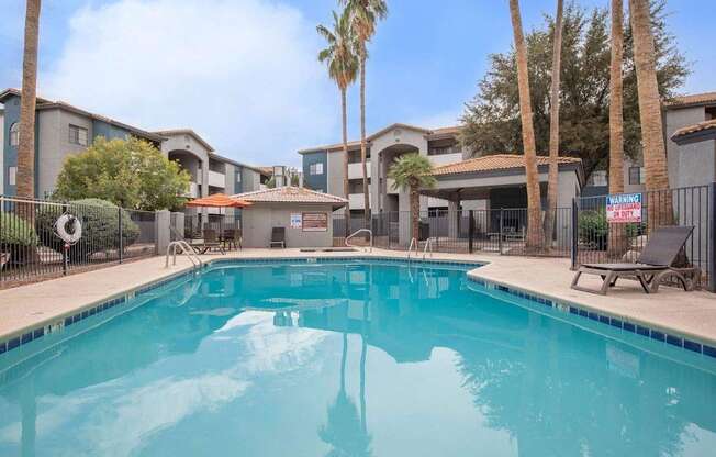 A swimming pool in front of a building with palm trees.