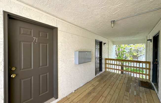 a front porch with a wooden floor and a door with a handle