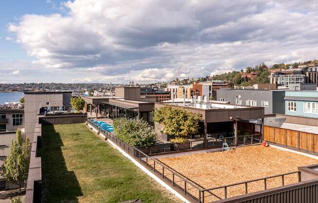 a view of a city from a roof top with a pool and a grassy area